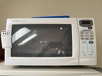 Front view of white Sharp Carousel microwave oven with large viewing window, control panel on right side.