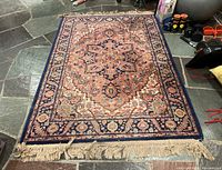 Full view of Karastan multi-colored patterned rug with fringe and visible wear on stone floor.