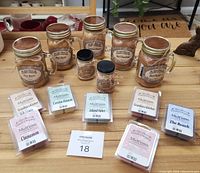 Photo of all candles and wax melts displayed on wooden table with auction number 18.