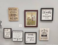 Six framed signs with bathroom-related humorous and inspirational texts, plus one framed pastoral scene