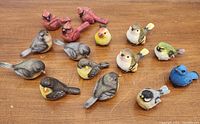 Photo of all 14 resin bird figurines displayed on wooden surface, showing various species and colors