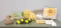 Lot of new bee-themed decor items including handmade pieces, cosmetic bags, and coin purses displayed on a table