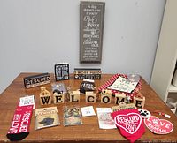 Full view of dog lovers lot items arranged on table including welcome blocks with dogs, decorative signs, tea towel, socks, and badges.