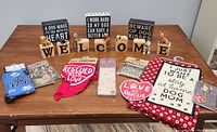 Photo showing all dog-themed items including wooden letter blocks, figurines, decorative signs, bandana, tea towels and pins arranged on a wooden table.