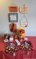 Front view of the lot showing wooden fall signs on wall, pumpkin centerpiece, tea towels, potpourri bags, and small pumpkin decor on table