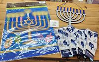 Photo of Hanukkah lot showing one garden flag, one wooden menorah decoration, and four pairs of Hanukkah themed socks on a wooden surface.