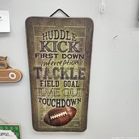 Football themed metal sign with football plays terms and football image hanging on wall