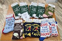 Photo showing eleven pairs of new socks by Primitives by Kathy with various text and graphics