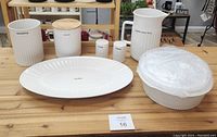 Photo showing all items: large oval platter, two canisters with wooden lids, a large pitcher, salt and pepper shakers, and two casserole dishes.