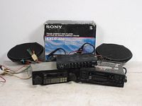Photo of Sony EXCD-406 FM/AM CD player box, AWE EQ-317 equalizer, two vintage car stereos, and oval speakers with wiring visible.
