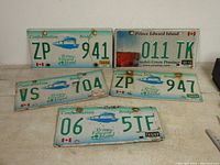 Six retired Prince Edward Island license plates arranged on a table, showing various designs and dates