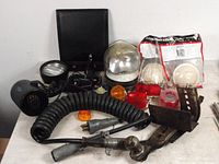 Wide shot of all trailer parts and truck driver accessories arranged on a table including a log book binder, fan, trailer lights, lens covers, metal bracket, hitch ball, and coiled cable.