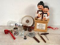 Full lot view showing all barware items including bar tool holder with bartender figurines, glassware, jiggers, hippo jar, and bar tools.