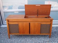 Front view of wood veneer console with sliding panel opened to show controls and turntable