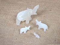 Four white quartz carved elephants on burlap surface showing sizes and arrangement.