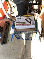 Central Pneumatic stapler box on top of blue multi-drawer hardware storage box next to other items in garage