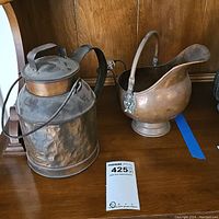 Front and right side view of the vintage hammered copper milk can next to the Dutch copper coal scuttle bucket on wooden surface.