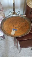 Full view of large round copper tray on small table, scalloped edges visible