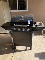Full front view of the Char-Broil grill on wheels with attached side shelves and propane tank underneath.