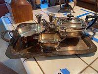 Photo of the full silver plated tea set on the tray including the teapot, dishes, and candle sticks.