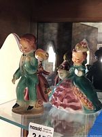 Photo of the full set of three vintage porcelain figurines on display shelf.