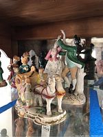Porcelain figurines showing horse-drawn carriage and dancing couple from front angle