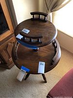 Top view of the vintage two tiered round wooden table showing the curved handles on the top tier and the two-tier construction