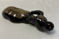 Glossy black and tan painted Shoushan clay cow sculpture viewed from above showing textured body and curled horns.