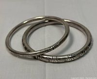 Two sterling silver bangles stacked showing etched patterns and overall condition.
