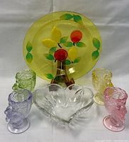 Full view showing Mikasa crystal heart bowl, decorative fruit-themed plate, and four colored Fenton glass bunny egg cups