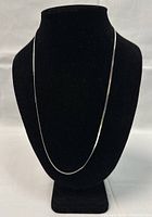 Full length of silver necklace displayed on black stand showing shape and shine.
