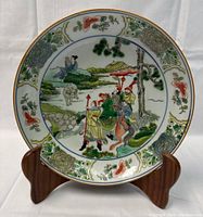 Front view of bowl on wooden stand showing central hand painted scene and floral border