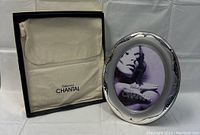 Photo frame standing outside box with dust cover in background.