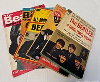 Five vintage Beatles paperback books stacked together showing covers with photos of The Beatles band members.