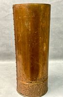 Front view of the copper umbrella stand showing patina and riveted side seam.