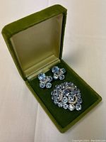Brooch and earrings displayed in green velvet box