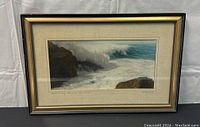 Frontal view of framed print showing ocean waves crashing on rocks and overall frame condition.
