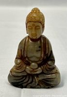 Front view of the small jade Buddha figurine showing seated meditative pose and carved details.