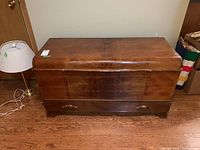 Front view of closed cedar chest showing wood veneer grain and lower drawer face