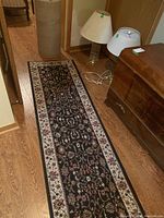Photo showing one of the carpet runners laid out on wooden flooring near lamps and furniture, displaying floral pattern and border detail.
