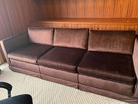 Full view of brown upholstered 3-seat couch showing cushions and armrests in wood-paneled room.