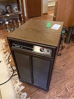 Front and side view showing woodgrain finish, control panel, and vented front grills.