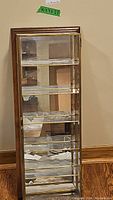 Front view of wooden framed display cabinet with mirrored interior and glass shelves