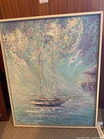 Framed painting showing a sailboat on water with an impressionistic sky using blues, purples, and creams.