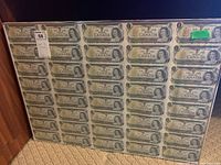 Full view of the framed sheet showing thirty Canadian one dollar bills arranged in six columns and five rows