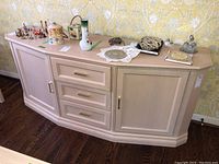 Wide angle of the full sideboard showing three drawers in the center and two cabinet doors on each side. Various decorative items placed on top are not included.
