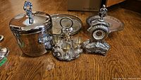 Photo of silver ice bucket, egg cruet set, mantle clock, and serving tray on wooden floor