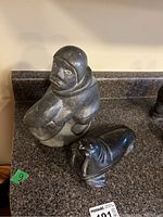 Two soapstone Inuit carvings showing a standing figure and a smaller seal figure on a granite countertop.