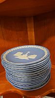 Stack of 15 light blue Wedgwood Christmas plates with white relief designs showing thickness and quantity