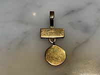 Front view of pendant showing rectangular bar and circular disc on marble background